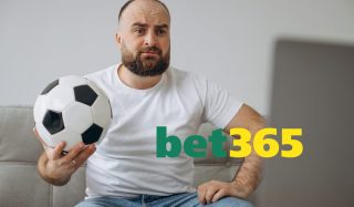 homem-segurando-uma-bola-de-futebol-e-assistindo-futebol-online-em-casa
